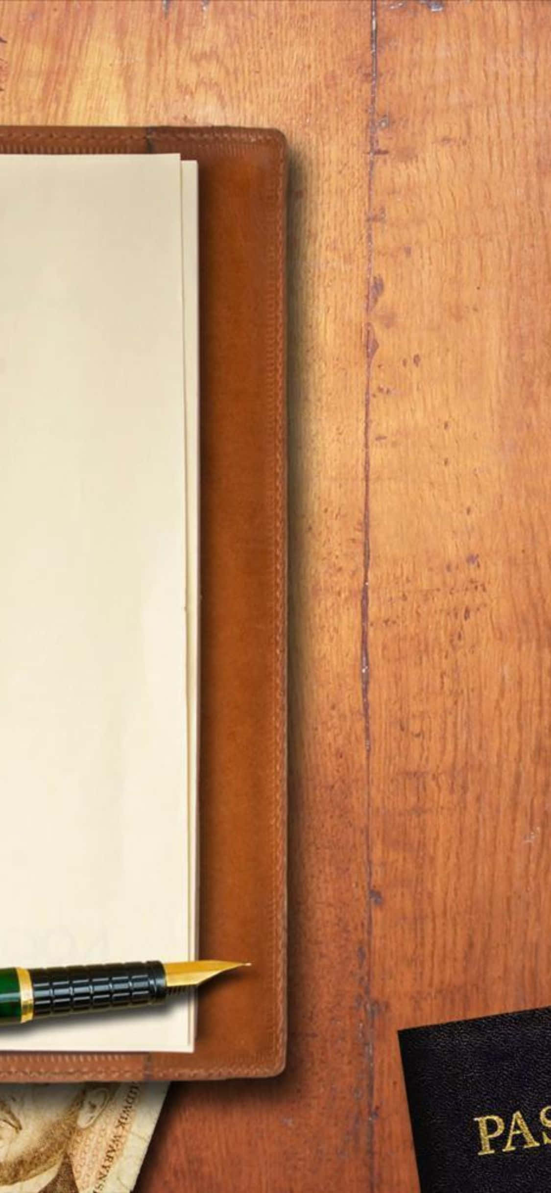 un pasaporte y un bolígrafo sobre una mesa de madera Fondos de pantalla