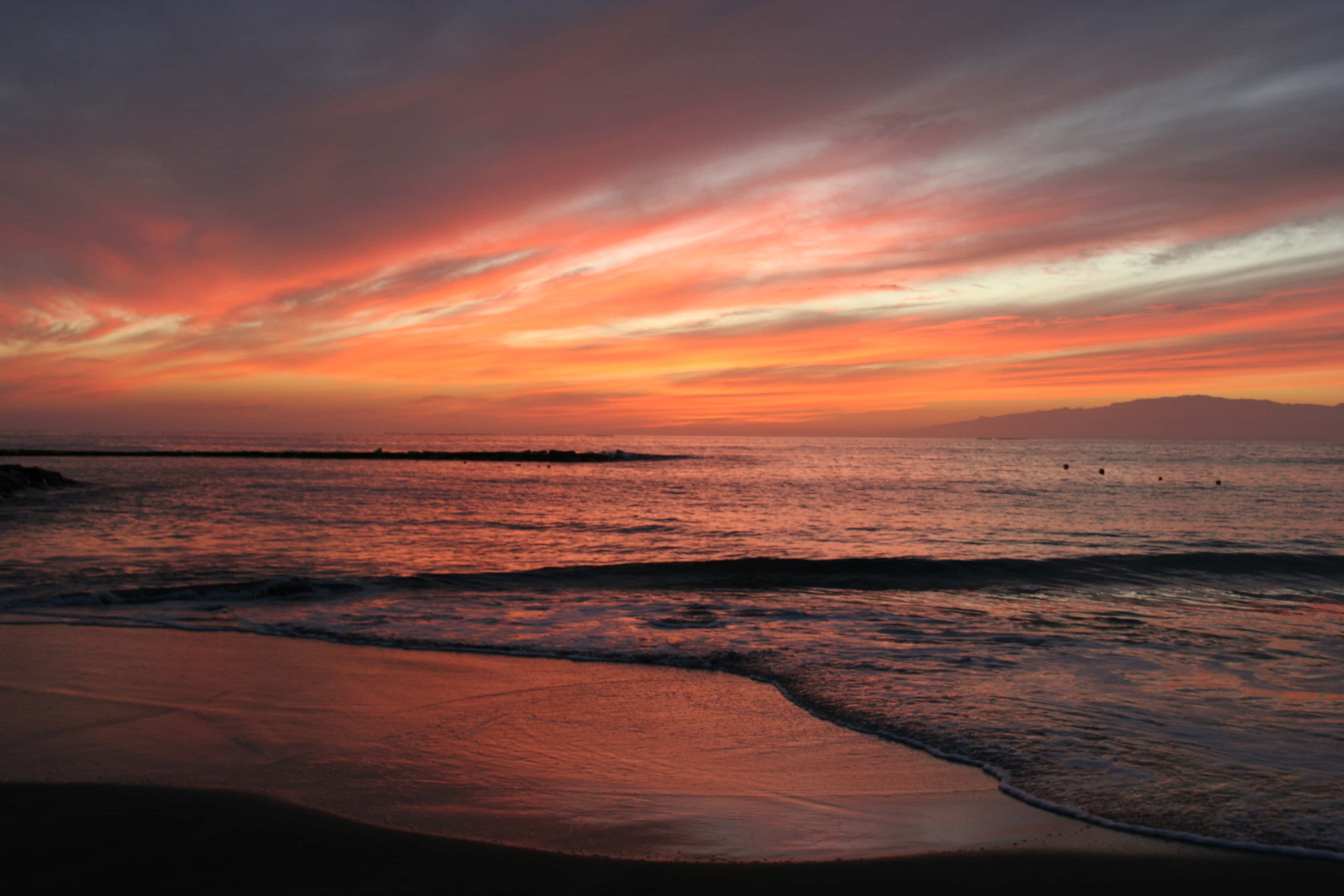 Un vibrante atardecer en la playa con hermosos tonos naranja, dorado y azul Fondos de pantalla