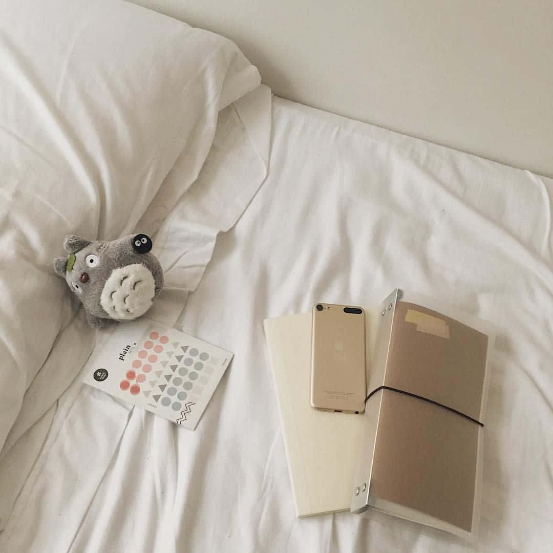 una cama blanca con un osito de peluche y una libreta Fondos de pantalla