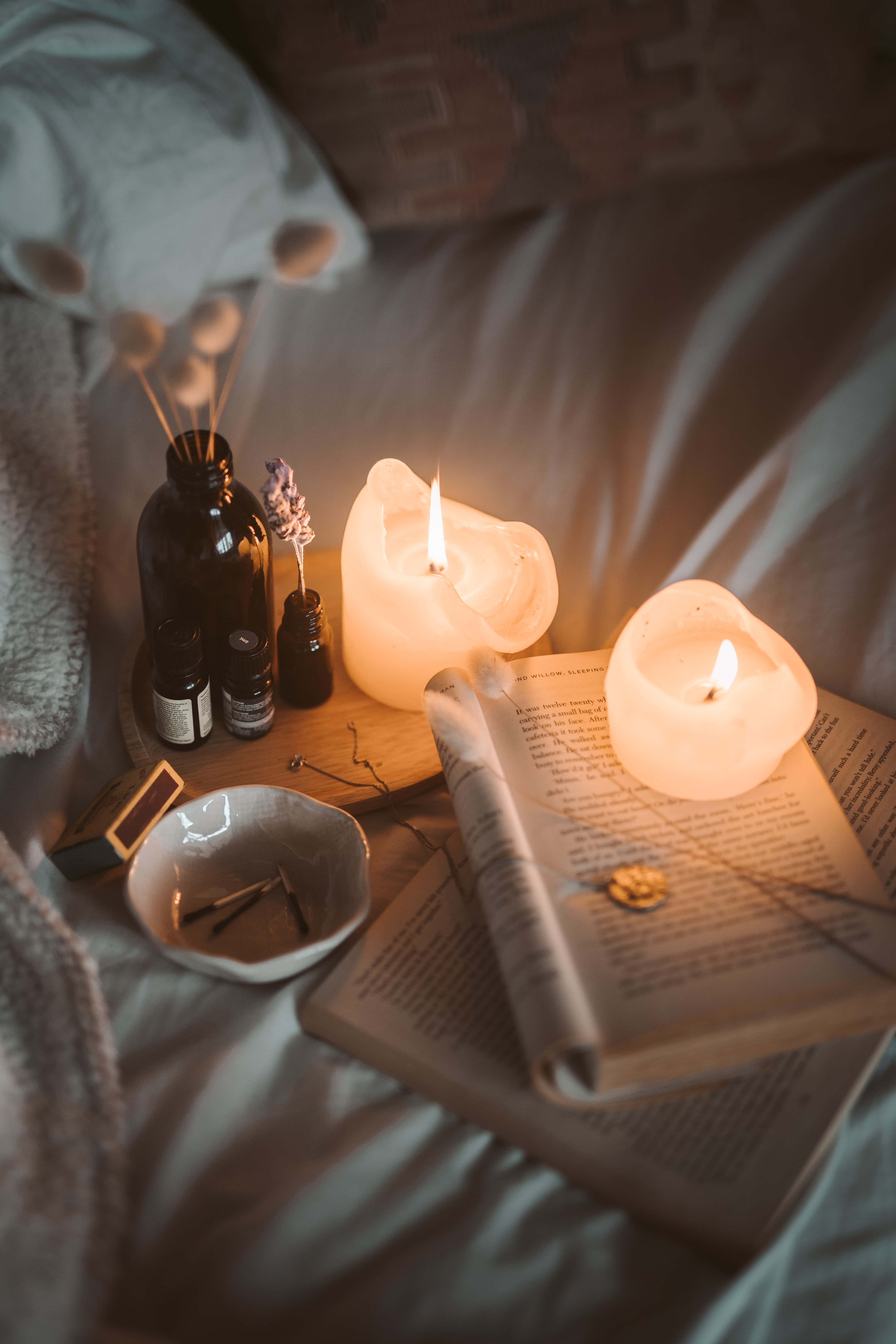 una cama con velas, un libro y una vela Fondos de pantalla
