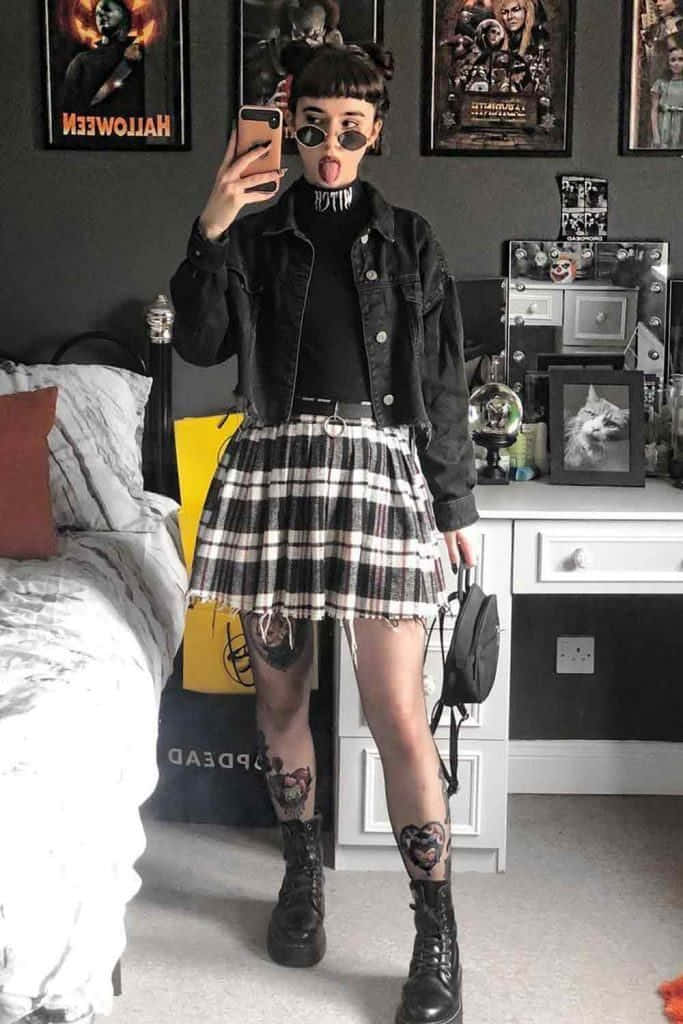 una chica con falda a cuadros y chaqueta negra tomándose una selfie Fondos de pantalla