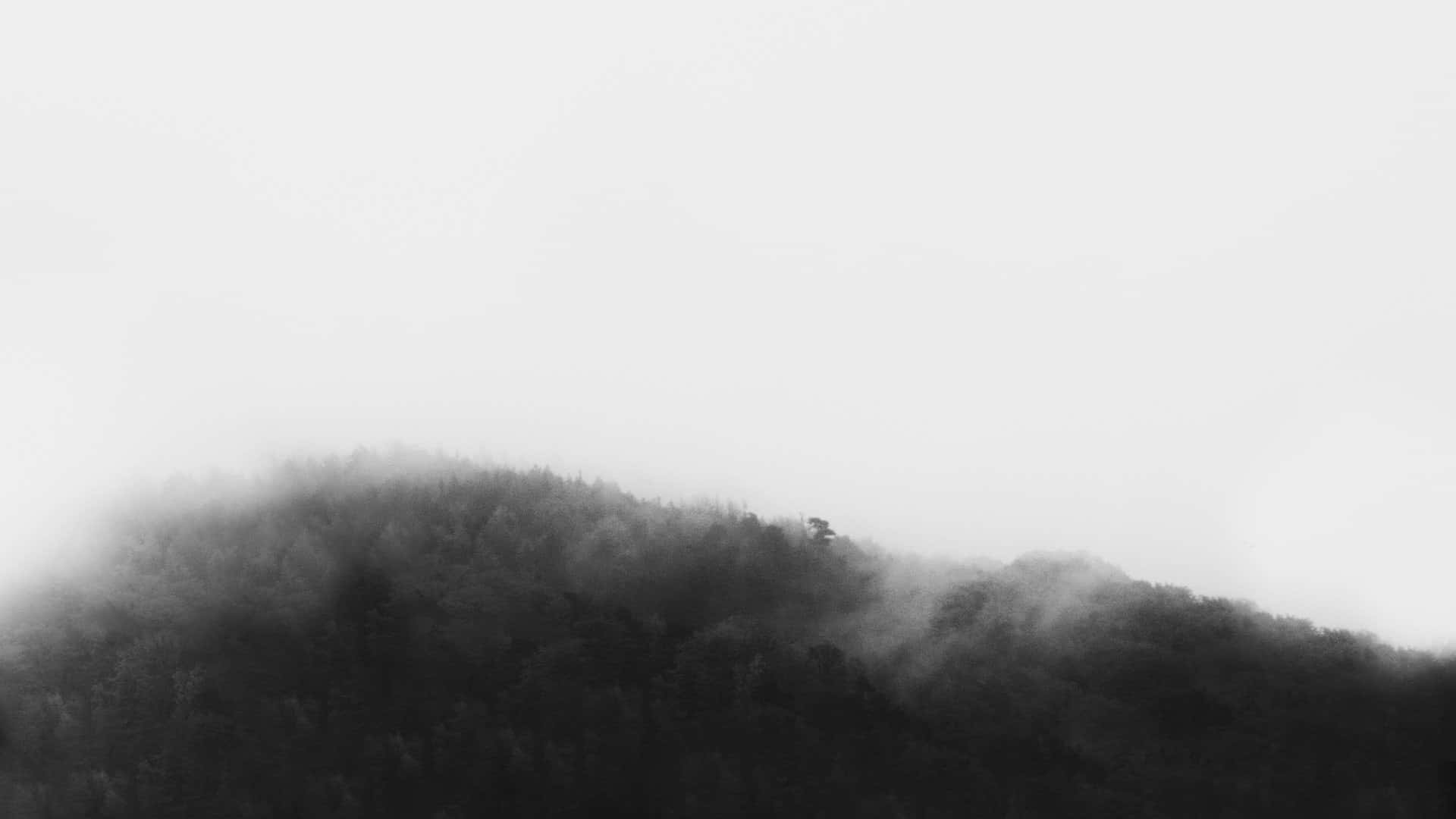 una foto en blanco y negro de una montaña cubierta de niebla Fondos de pantalla
