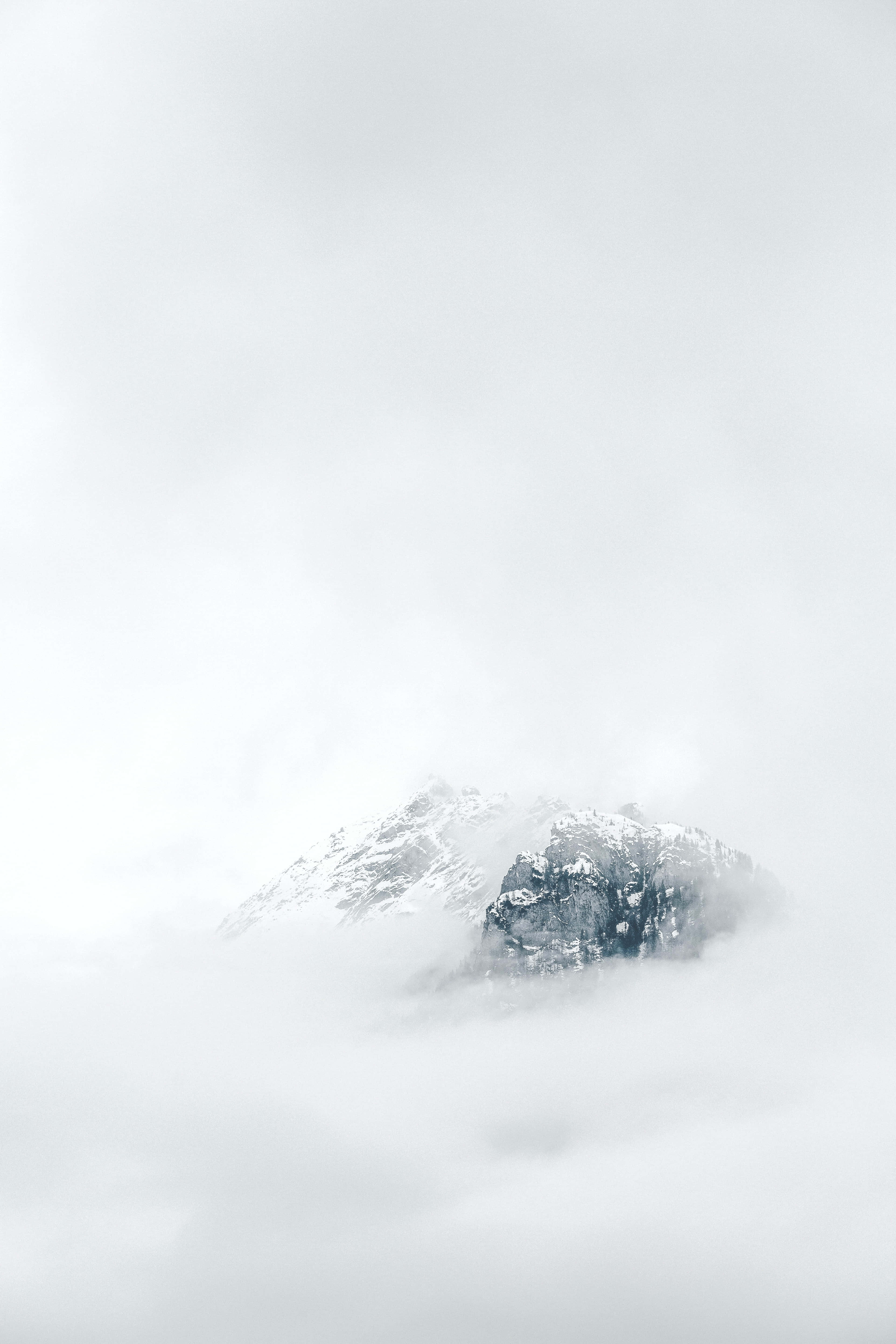 una montaña cubierta de nubes con nieve en la cima Fondos de pantalla
