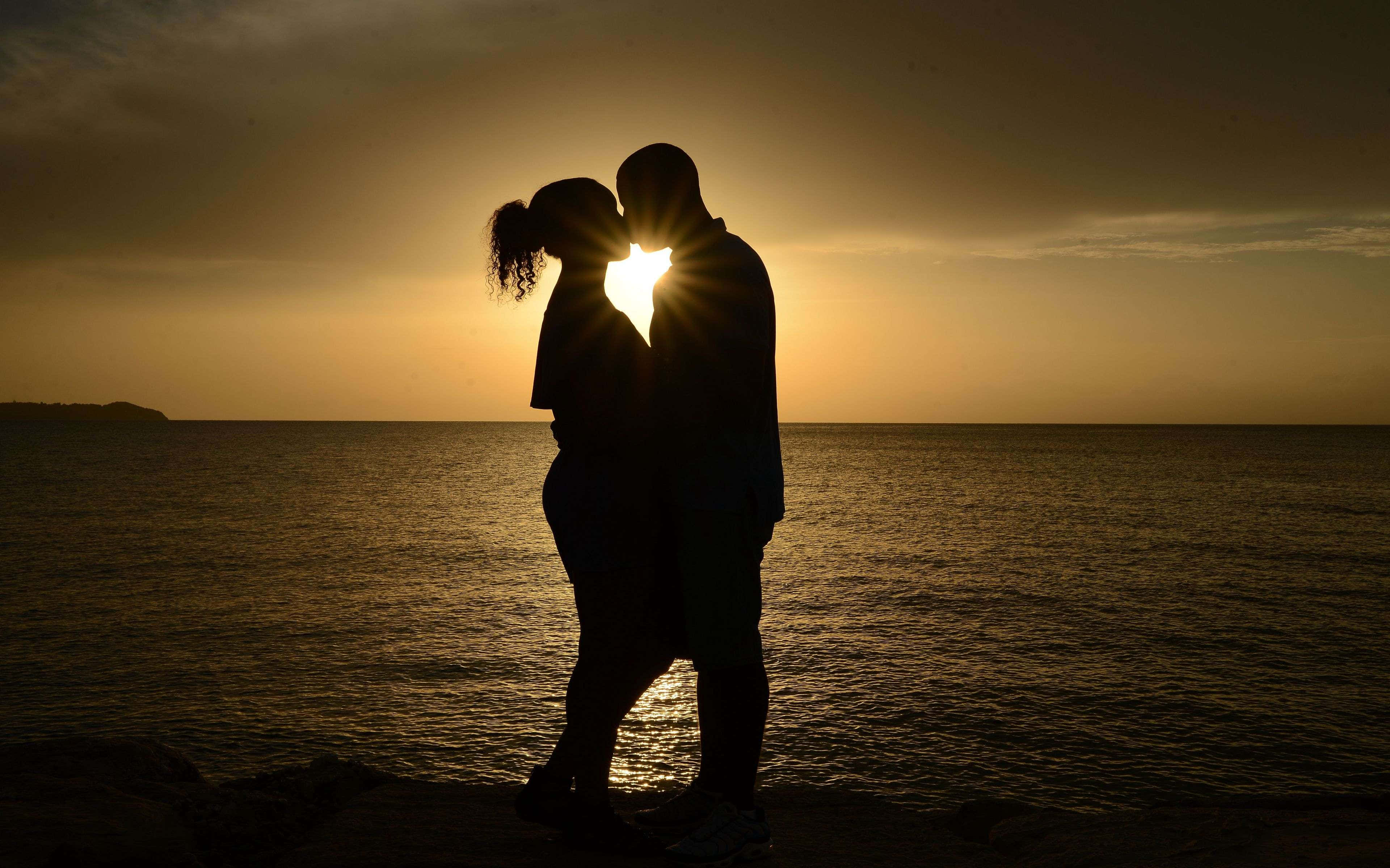 Una pareja romántica abrazada junto a un hermoso atardecer Fondos de pantalla
