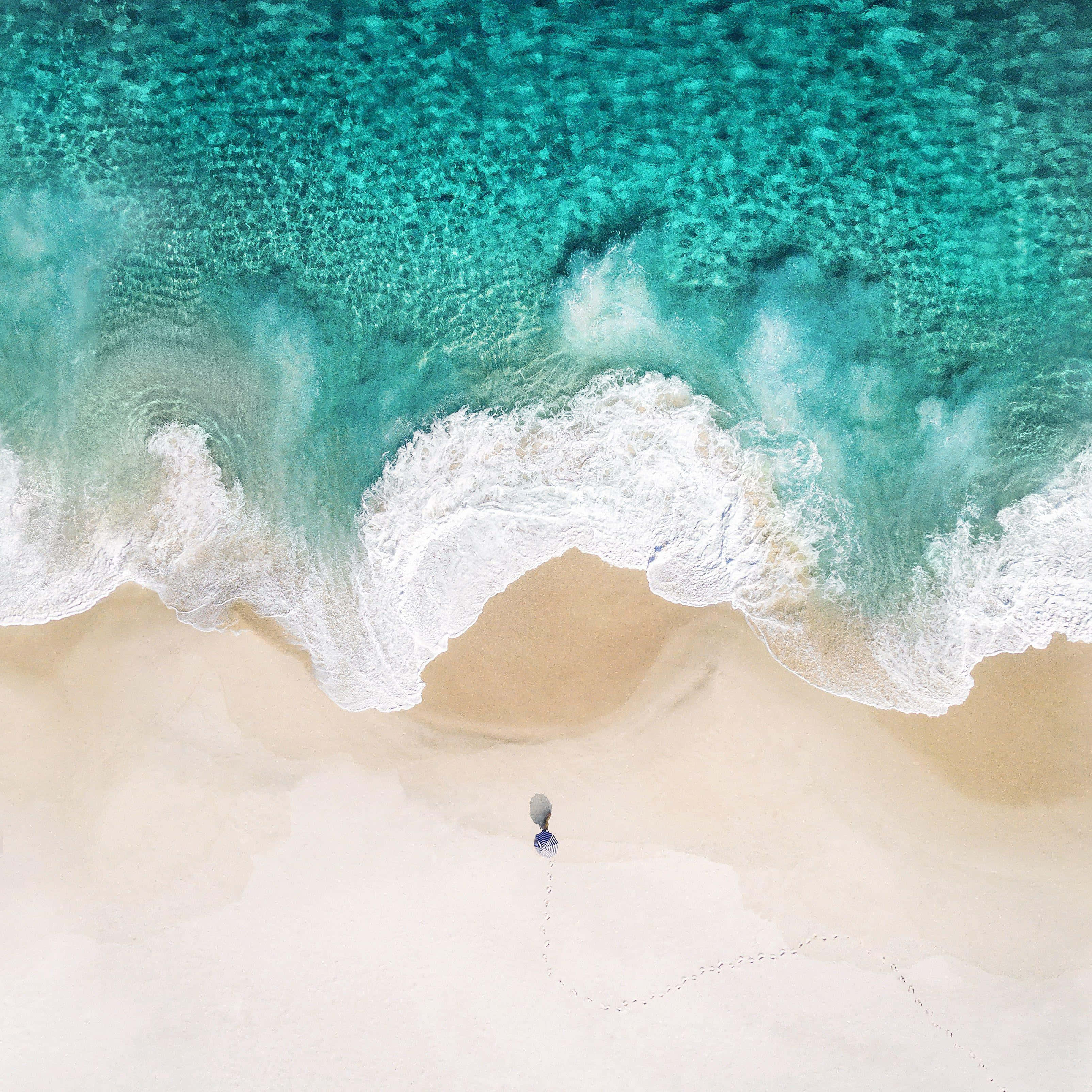 una persona camina por la playa cerca del océano Fondos de pantalla