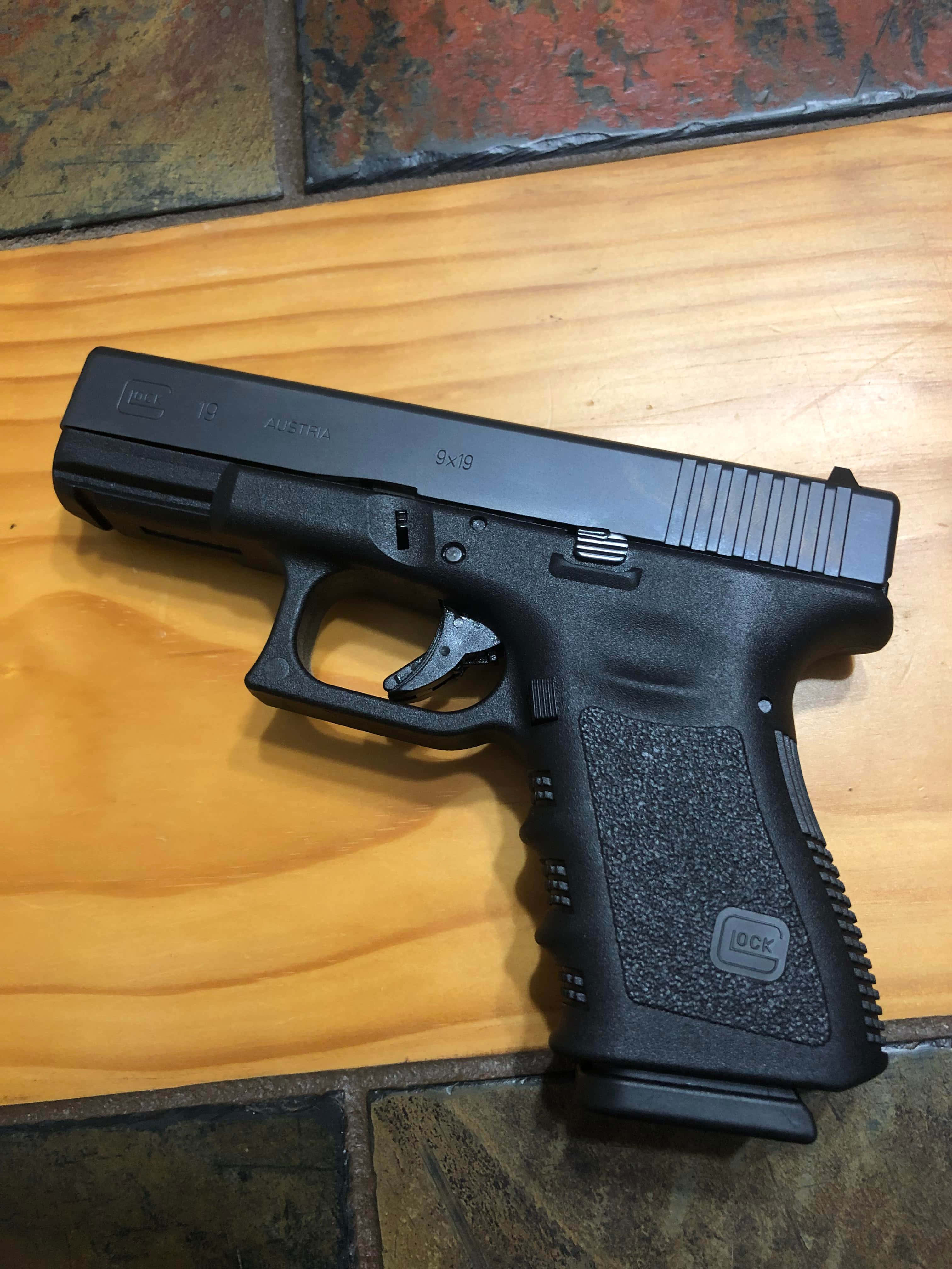 una pistola Glock negra sobre un piso de madera Fondos de pantalla
