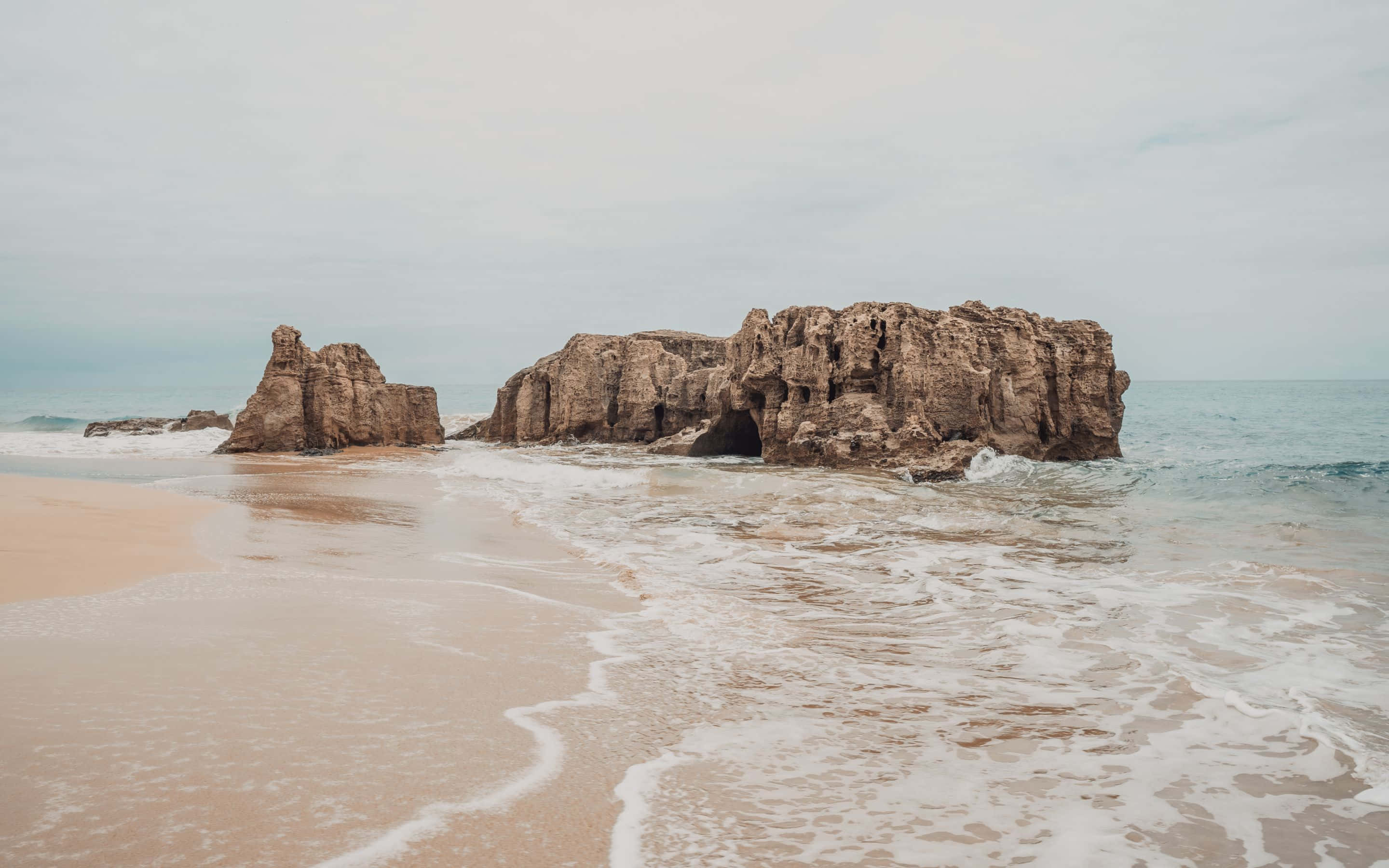 una playa con rocas y olas Fondos de pantalla