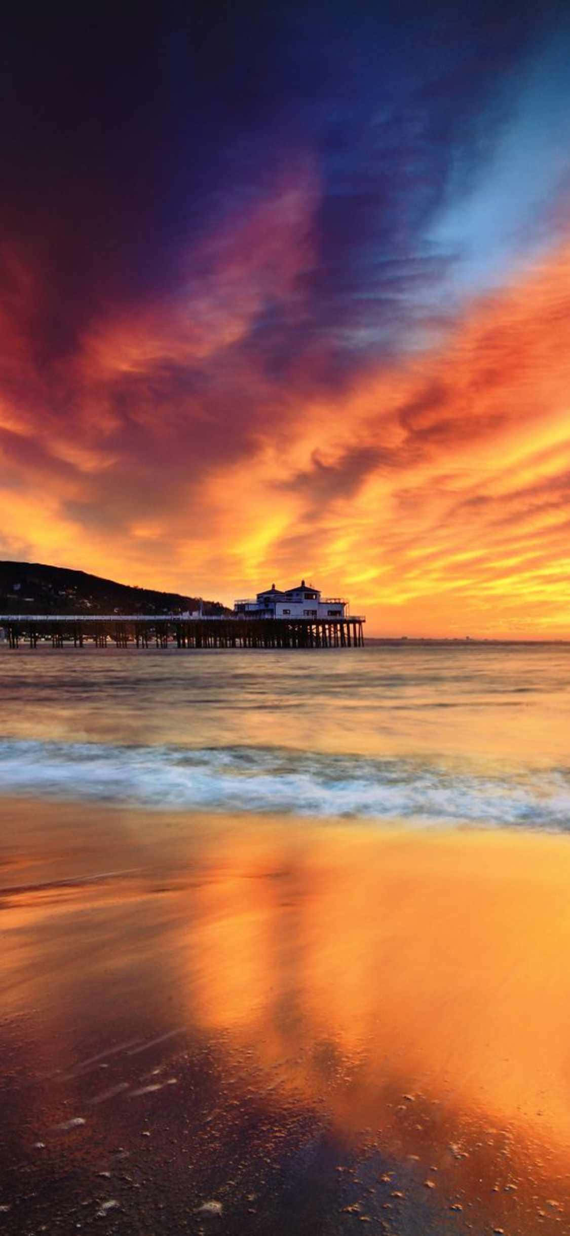 una puesta de sol sobre el océano con un muelle al fondo Fondos de pantalla