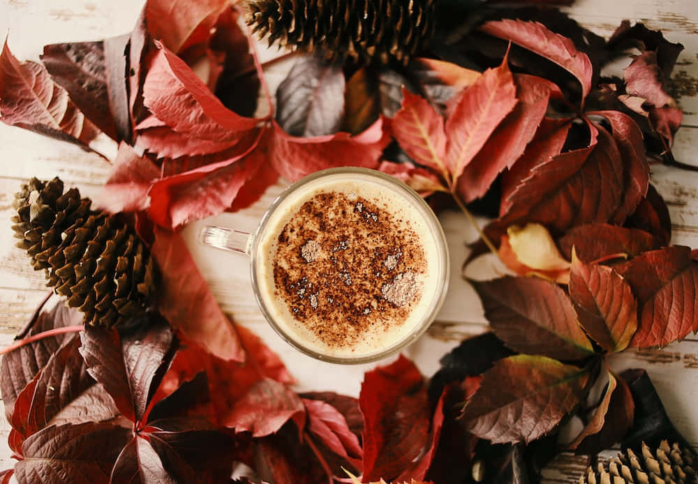 una taza de café rodeada de hojas y piñas Fondos de pantalla