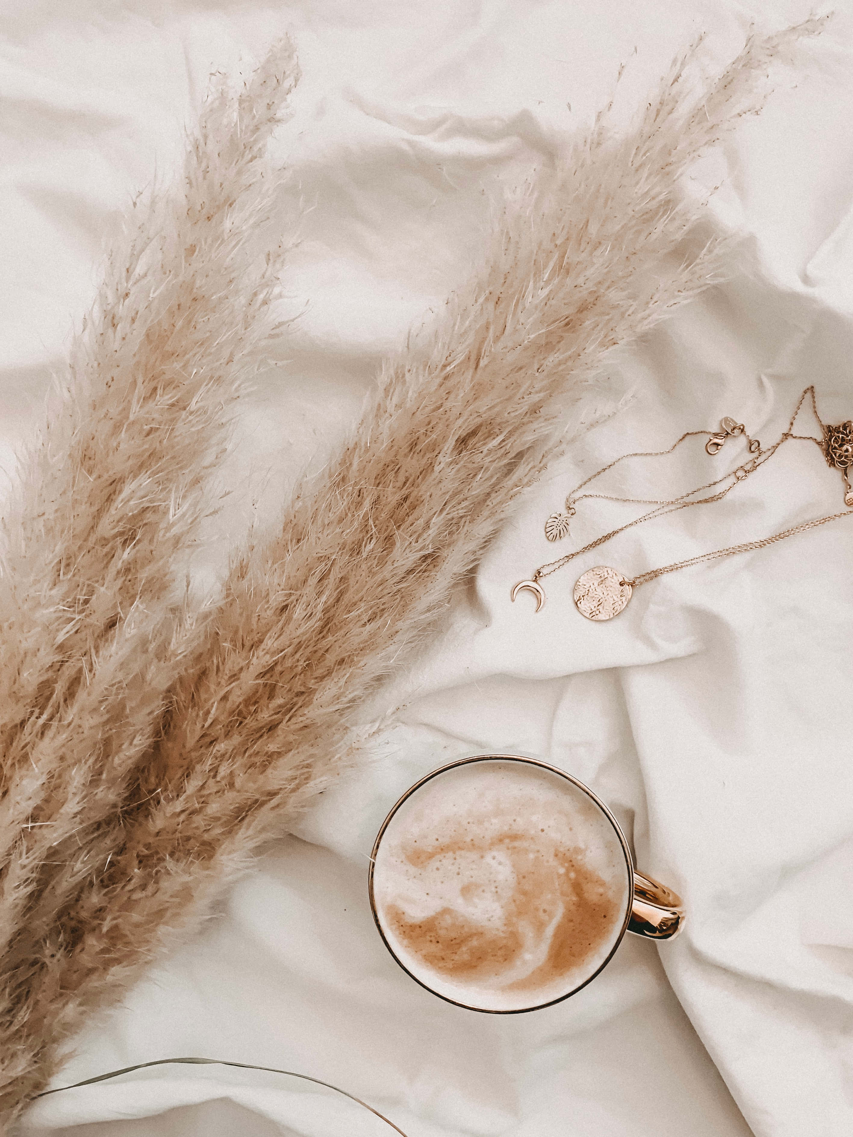 una taza de café y un collar sobre una cama Fondos de pantalla