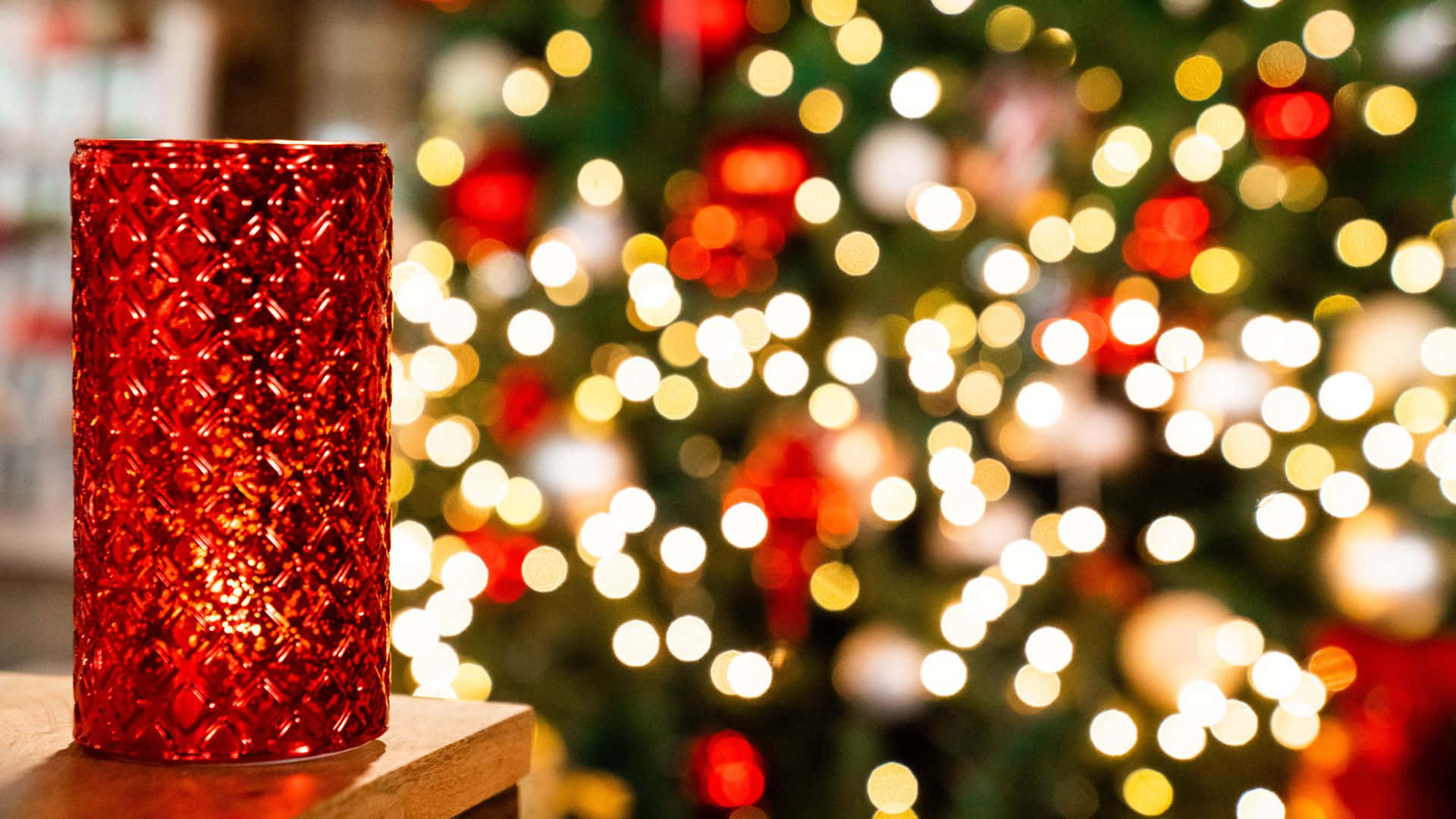 una vela roja sobre una mesa frente a un árbol de navidad Fondos de pantalla