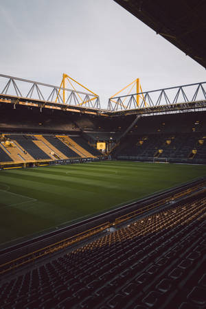 Fondo de pantalla móvil de estadio de fútbol vacío iluminado por la luz del sol.