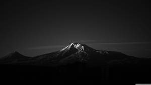 Fondo de pantalla 4K de una pequeña montaña rocosa oscura.
