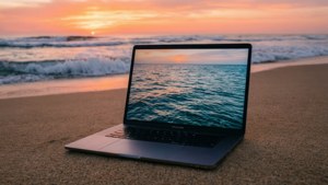 Una serena MacBook en una playa durante el amanecer con tonos oceánicos.
