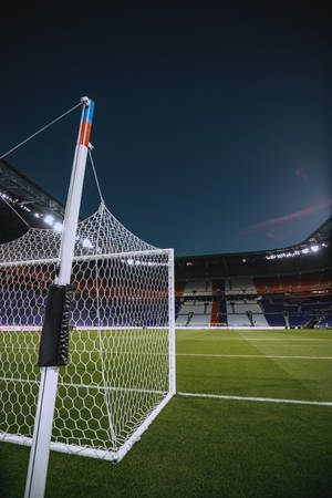 Fondo de pantalla móvil de estadio de fútbol con poste de gol y cielo nocturno.