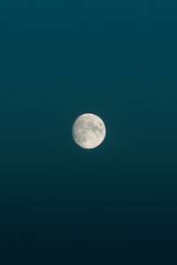 Brillo de la luna llena durante la medianoche en un cielo azul de estética minimalista. Luna y su superficie visible.