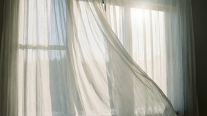 Cortinas blancas y translúcidas ondeando con la luz del sol, un fondo de pantalla etéreo y relajante.