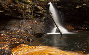 Fondo de pantalla de una cascada con un río rocoso oscuro.
