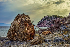 Fondo de pantalla de playa rocosa y sombría.