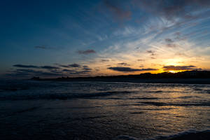Atardecer en el mar con aguas claras y un cielo azul.