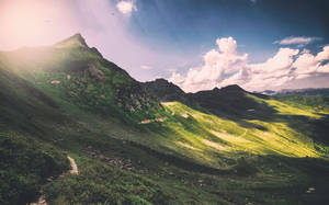 Montaña verde con paisaje limpio y nubes blancas, efecto panorámico.