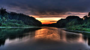 Fondo de pantalla de río tranquilo en la selva bajo un cielo naranja al atardecer