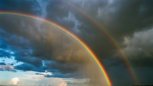 Doble arcoíris apareciendo después de la tormenta con nubes oscuras al fondo. — Vista del cielo Fondos de pantalla