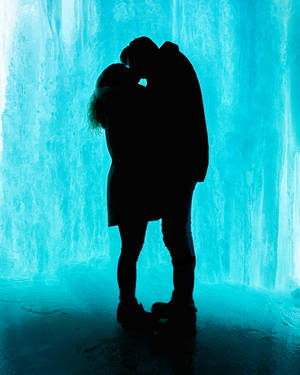 Silueta de pareja besándose enamorada contra fondo de hielo azul. Amantes besándose en el Día de San Valentín.