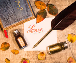 Inscripción naranja "Amor" escrita en un trozo de papel blanco con pluma y frascos de tinta sobre una mesa de madera. Carta de amor para el Día de San Valentín.