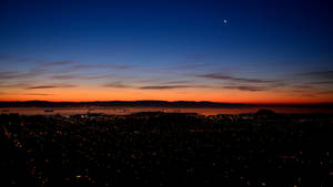 Fondo de pantalla de luces de la ciudad y luna nocturna en el cielo