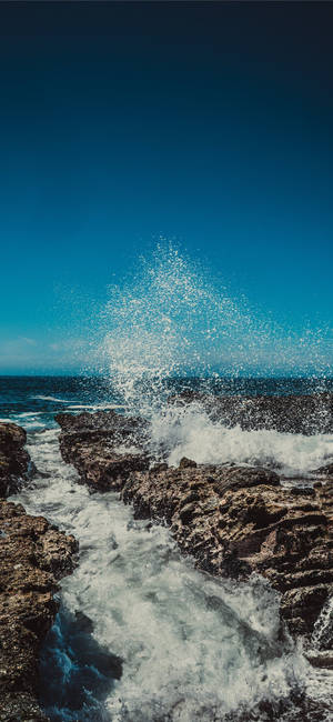 Fondo de pantalla de olas rompiendo en rocas para iPhone 11.