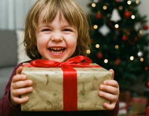 Un niño feliz abrazando un regalo de Navidad, lleno de alegría y anticipación. — Regalos de Navidad Fondos de pantalla
