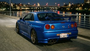 Fondo de pantalla de Un Nissan GT-R azul en un puente de noche con reflejos de la ciudad.