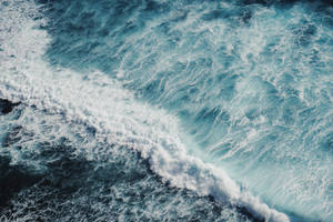 Océano azul con olas y espuma de agua de mar en vista superior.