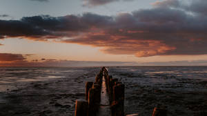 Atardecer en el océano con cielo oscuro, ambiente previo al horizonte vespertino en un muelle.