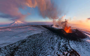 Volcano releasing smoke and fire during sunset.