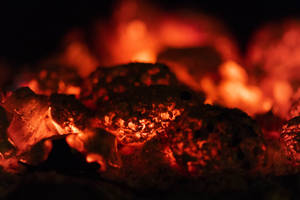 Primer plano de fuego abrasador y carbón. Carbón al rojo vivo iluminando la oscuridad.