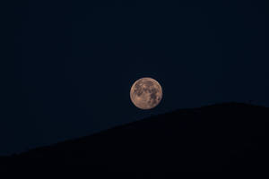 Luna llena brillando intensamente sobre las colinas. Foto minimalista de la luna y las tierras altas.