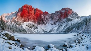 Paisaje invernal con montaña roja cubierta de nieve y lago congelado