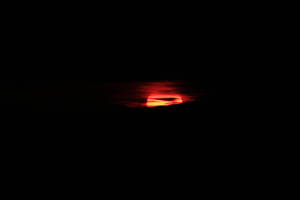 Atardecer rojo anaranjado detrás del horizonte negro.