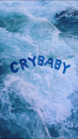 Fondo de pantalla azul estético con letras grandes de globo que dicen 'Crybaby' flotando en el océano o mar.