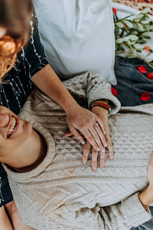 Pareja enamorada en una cita con el chico recostado en el regazo de la chica mientras se tocan las manos. Cita de picnic en el Día de San Valentín.