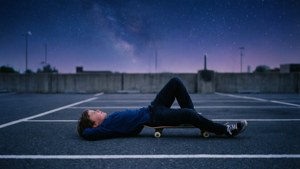 Un chico patinador relajándose bajo un cielo estrellado en un lote tranquilo. — Estética skater boy Fondos de pantalla