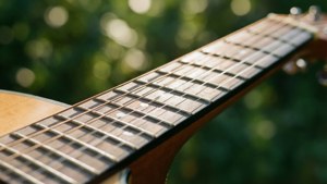 Primer plano de cuerdas de guitarra con bokeh verde y luz cálida del sol. — Estética musical Fondos de pantalla