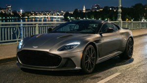Fondo de pantalla de Aston Martin DBS Superleggera en un puente de noche con luces de la ciudad.