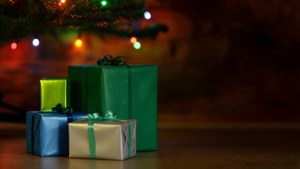 Coloridos regalos apilados bajo un árbol de Navidad con luces centelleantes. — Regalos de Navidad Fondos de pantalla