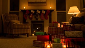 Montón de regalos envueltos variados frente a una chimenea con calcetines navideños. — Regalos de Navidad Fondos de pantalla
