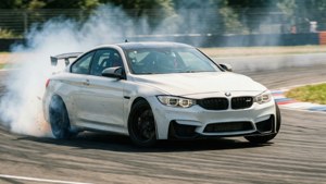 Un BMW M4 blanco derrapa en una curva de un autódromo con humo de llantas y desenfoque de movimiento. — Bmw Fondos de pantalla