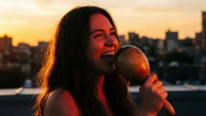Vivo interpreta una canción conmovedora en una azotea mientras el sol se pone, con una maraca en la mano.