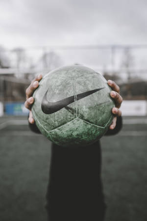 Fondo de pantalla móvil de un balón de fútbol en manos en primer plano.